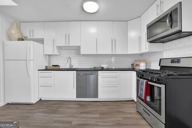 kitchen featuring sink, decorative backsplash, light wood-type flooring, white cabinetry, and stainless steel appliances