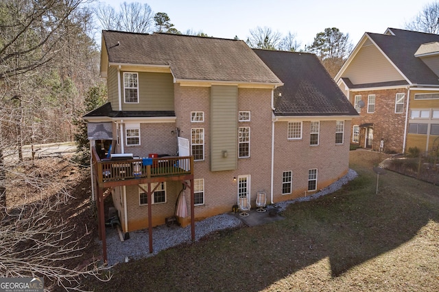 back of property featuring a wooden deck and a lawn