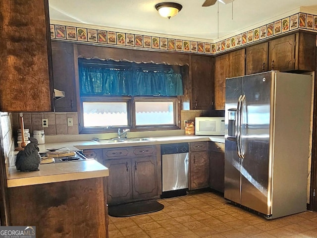 kitchen featuring dark brown cabinetry, appliances with stainless steel finishes, light countertops, and a sink