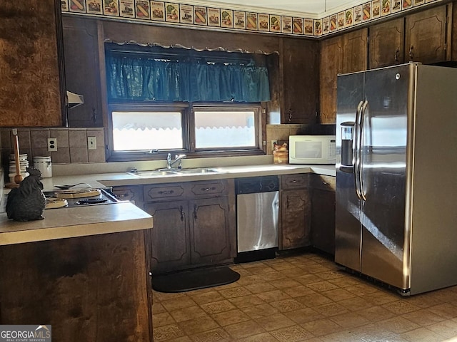 kitchen featuring stainless steel appliances, light countertops, a sink, and dark brown cabinets