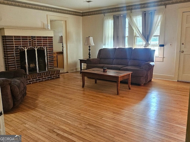 living area featuring ornamental molding, light wood finished floors, a tiled fireplace, and baseboards