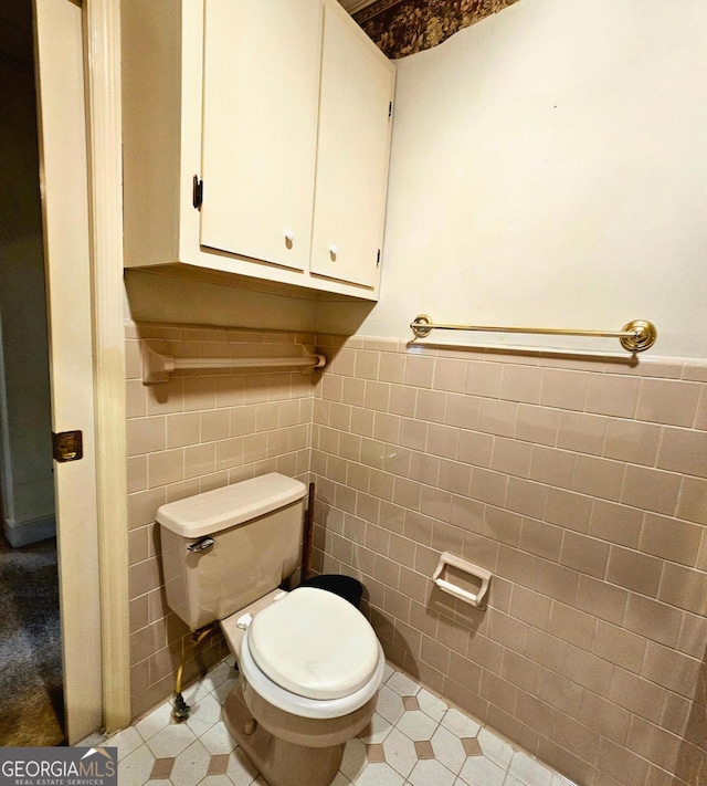 bathroom featuring a wainscoted wall, tile walls, and toilet