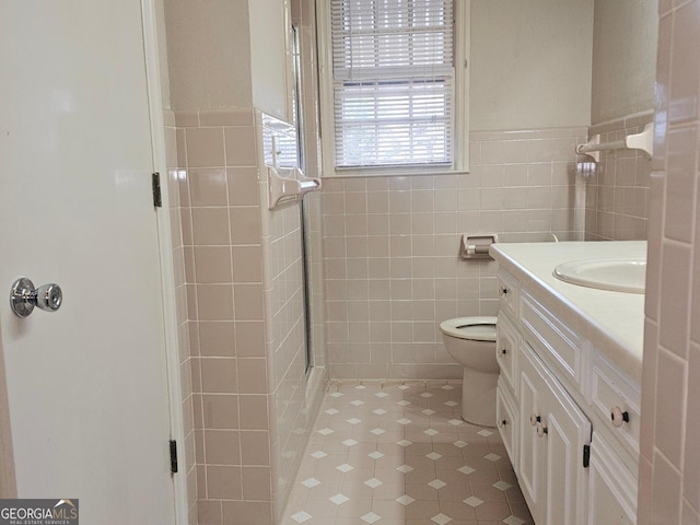 bathroom with tile walls, a stall shower, wainscoting, vanity, and tile patterned floors