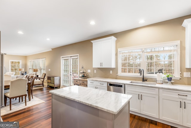 kitchen featuring dishwasher, sink, white cabinets, and light stone counters