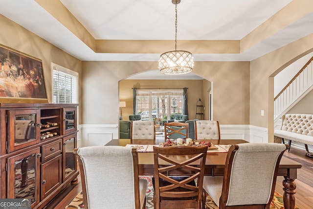 dining area with a tray ceiling, an inviting chandelier, and hardwood / wood-style flooring