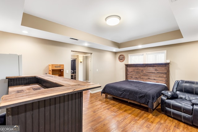 bedroom featuring light hardwood / wood-style floors and a raised ceiling