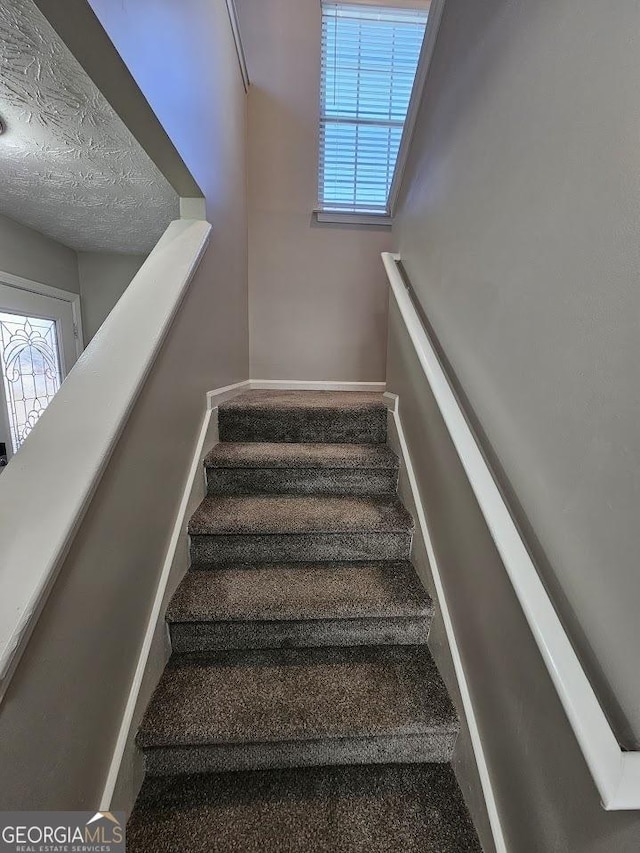 stairs featuring a textured ceiling