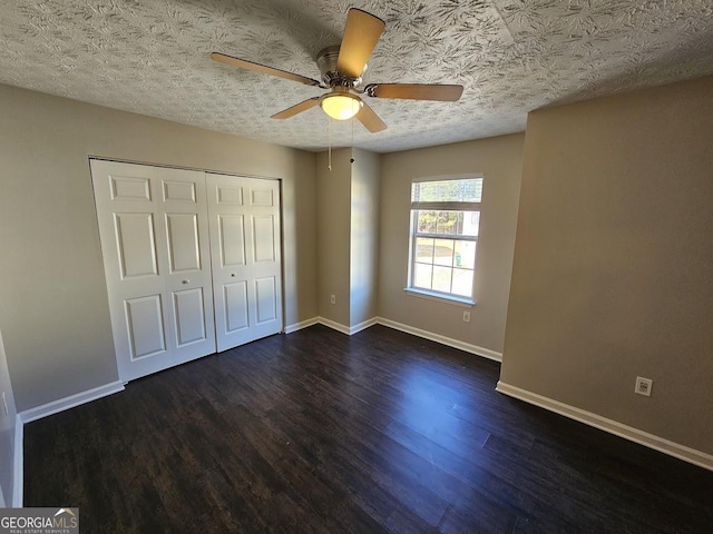 unfurnished bedroom with a textured ceiling, ceiling fan, a closet, and dark hardwood / wood-style floors