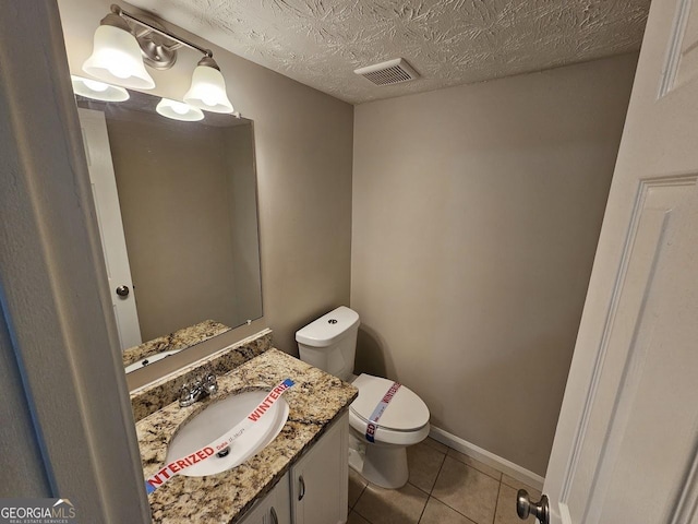 bathroom with toilet, a textured ceiling, tile patterned floors, and vanity