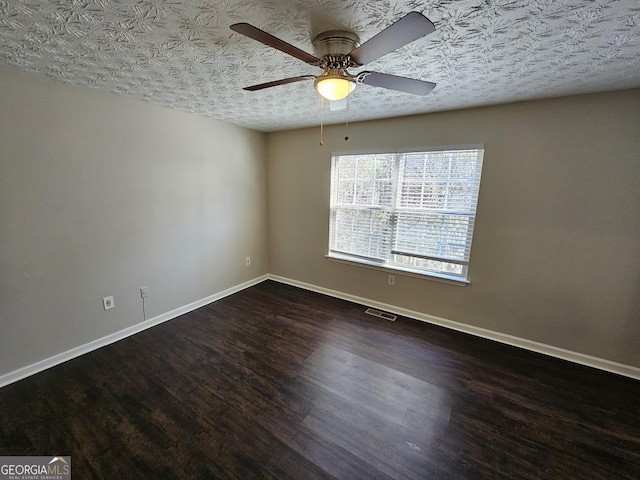 empty room featuring ceiling fan, dark hardwood / wood-style flooring, and a textured ceiling