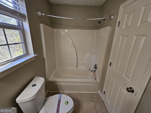 bathroom with bathing tub / shower combination, tile patterned flooring, and toilet