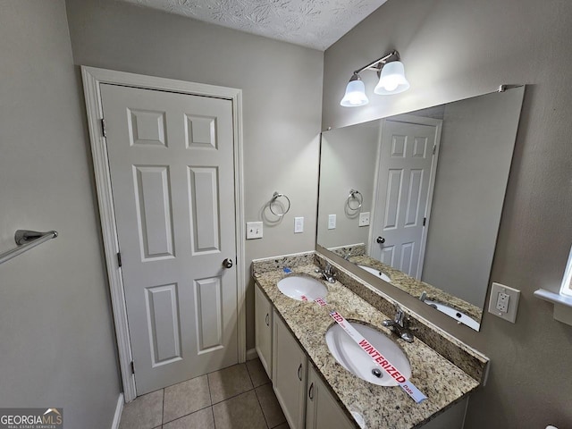 bathroom with a textured ceiling, tile patterned flooring, and vanity