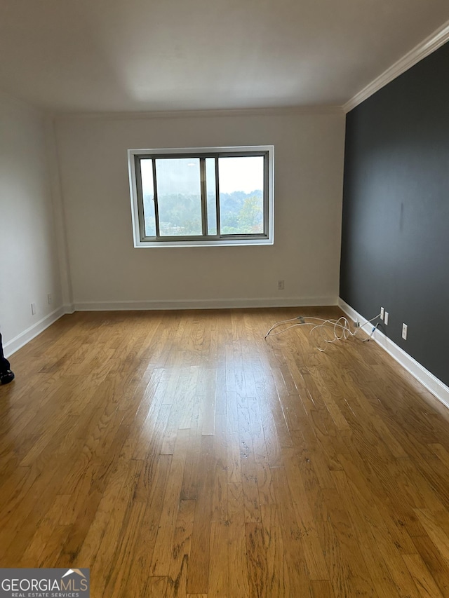 spare room featuring crown molding and light hardwood / wood-style floors