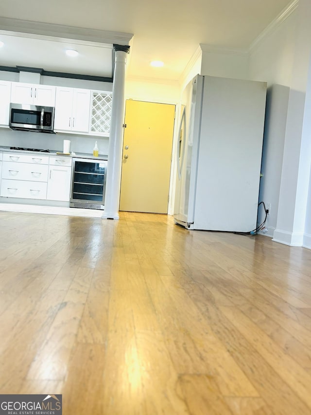 kitchen with wine cooler, gas stovetop, ornamental molding, white fridge, and white cabinetry