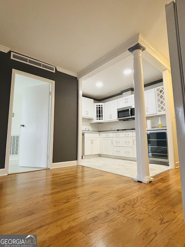 kitchen with wine cooler, white cabinetry, light hardwood / wood-style floors, and ornamental molding