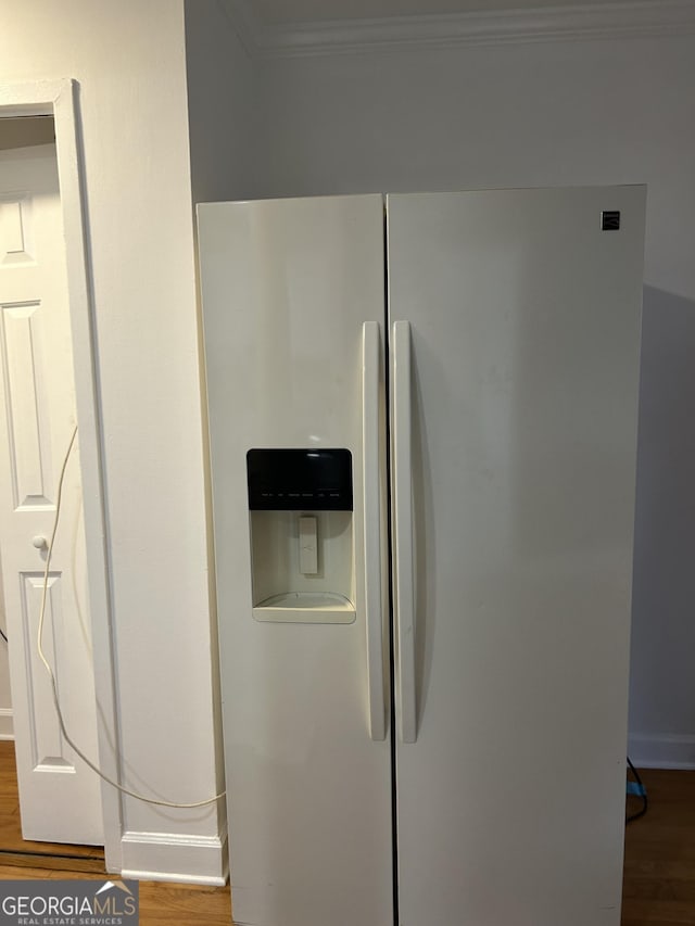 interior details featuring stainless steel fridge, wood-type flooring, and ornamental molding