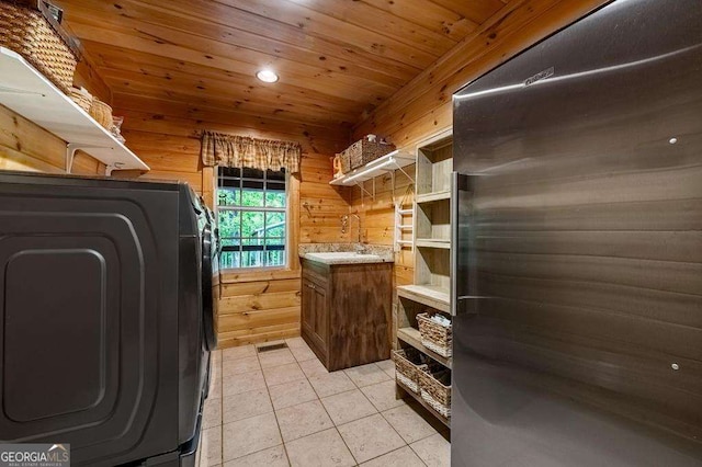 laundry area featuring wood walls, sink, light tile patterned floors, wood ceiling, and washer / clothes dryer