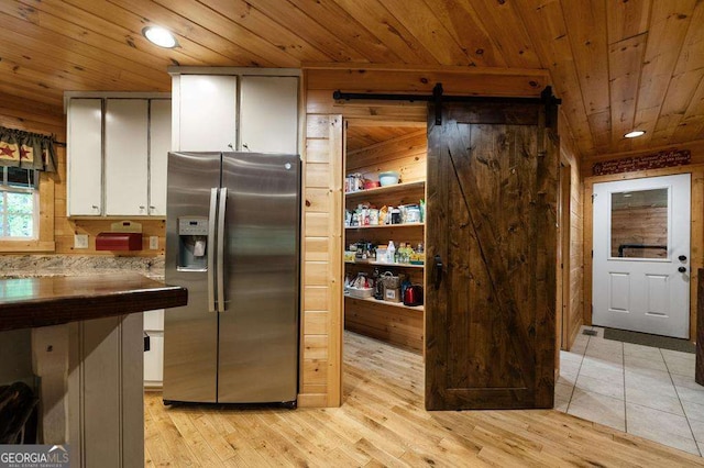 kitchen with a barn door, white cabinetry, stainless steel refrigerator with ice dispenser, and wood ceiling