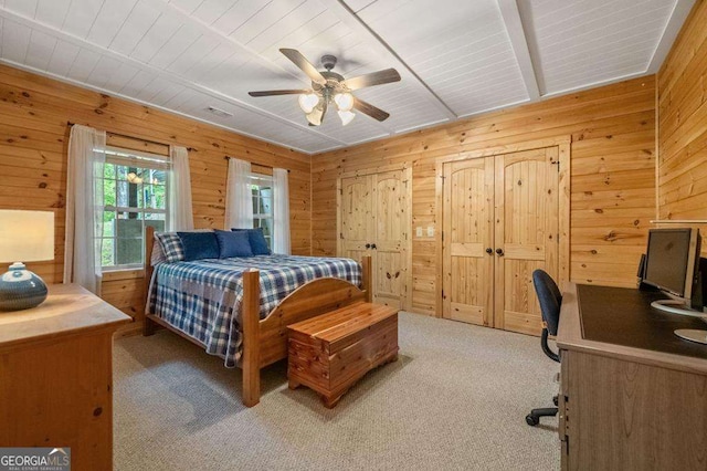 bedroom with wooden walls, ceiling fan, and light colored carpet