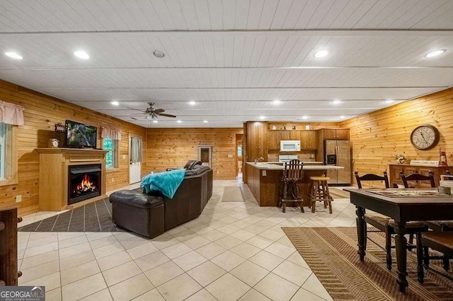 tiled living room featuring ceiling fan and wood walls