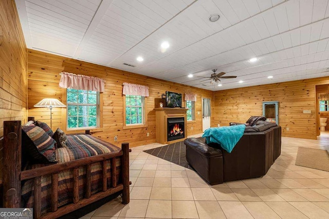 living room with ceiling fan, light tile patterned floors, and wooden walls