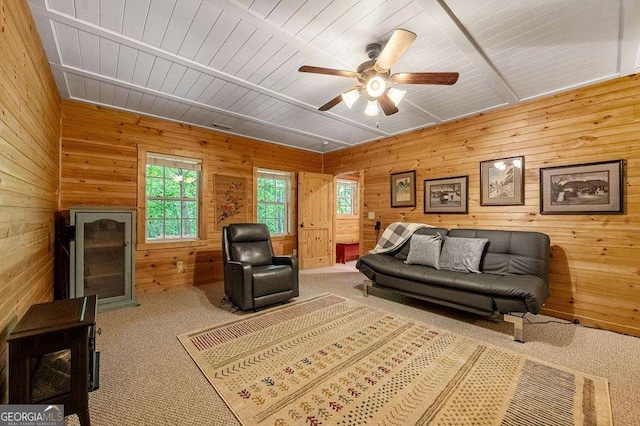 carpeted living room with ceiling fan, wooden ceiling, and wooden walls