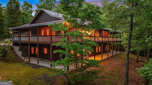 back house at dusk with a patio area and a wooden deck