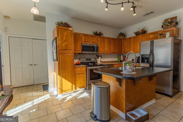 kitchen with a center island with sink, a breakfast bar, light tile patterned floors, and stainless steel appliances