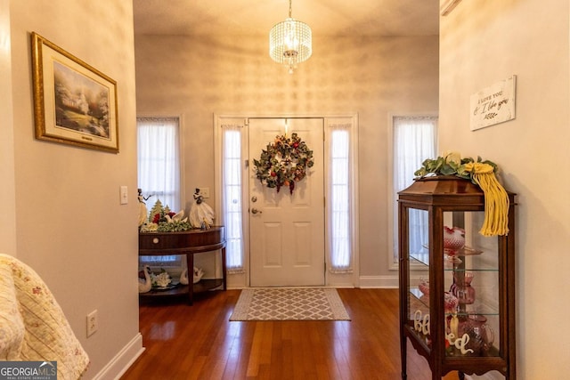 foyer entrance featuring a healthy amount of sunlight, dark hardwood / wood-style floors, and an inviting chandelier