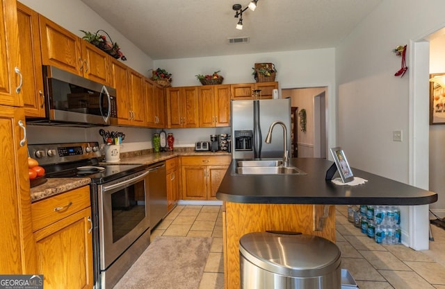 kitchen with sink, light tile patterned floors, appliances with stainless steel finishes, a kitchen island, and a breakfast bar area