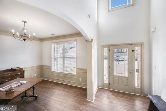 foyer featuring dark hardwood / wood-style flooring, an inviting chandelier, and crown molding