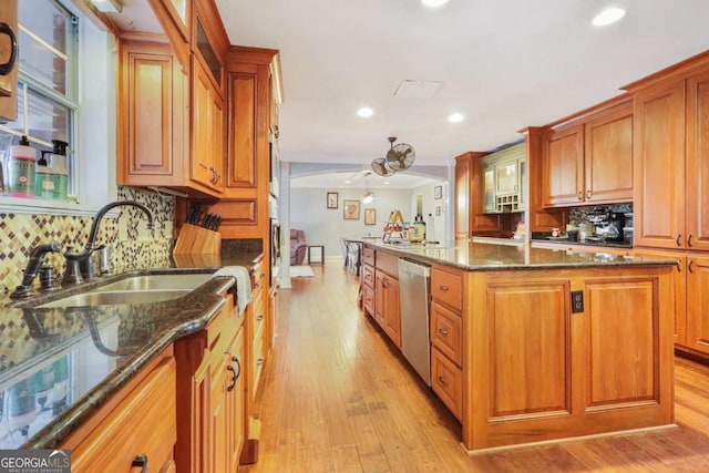 kitchen featuring stainless steel dishwasher, a kitchen island, sink, and dark stone counters