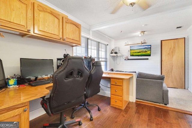 office space with ceiling fan, dark hardwood / wood-style flooring, a textured ceiling, wooden walls, and ornamental molding