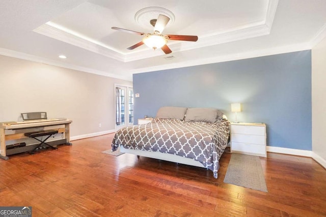 bedroom featuring hardwood / wood-style floors, ceiling fan, crown molding, and a tray ceiling