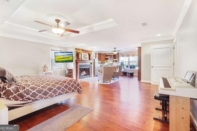 bedroom featuring a raised ceiling, hardwood / wood-style floors, and ornamental molding