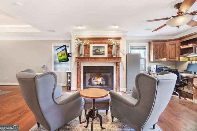 living room with ceiling fan, a fireplace, crown molding, and light hardwood / wood-style flooring