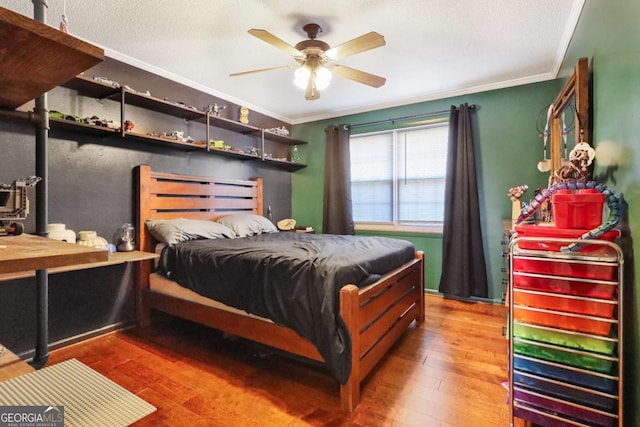 bedroom with hardwood / wood-style flooring, ceiling fan, ornamental molding, and a textured ceiling