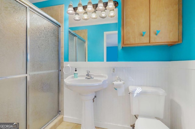 bathroom with toilet, a shower with shower door, and sink