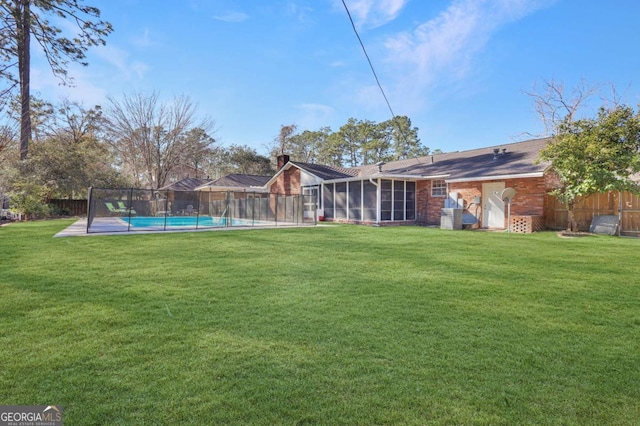 rear view of property featuring a fenced in pool, a lawn, and a sunroom