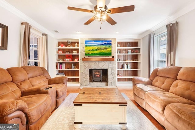 living room featuring built in shelves, ceiling fan, crown molding, and hardwood / wood-style floors