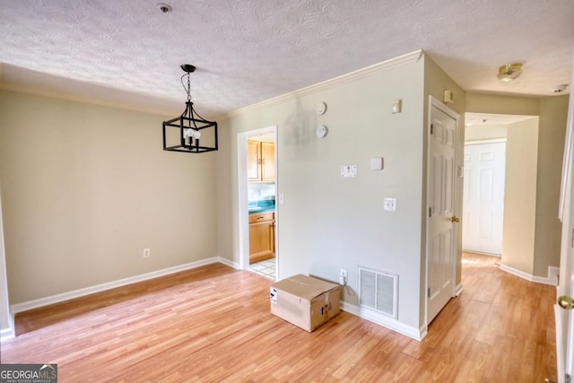 unfurnished dining area featuring light hardwood / wood-style flooring, a textured ceiling, and a notable chandelier