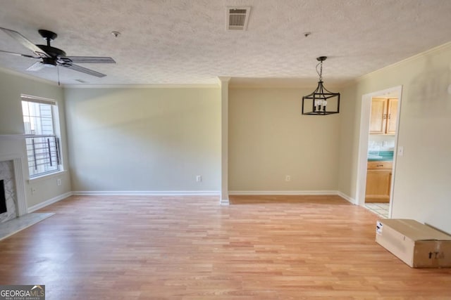 unfurnished living room with a premium fireplace, light hardwood / wood-style floors, a textured ceiling, and ornamental molding