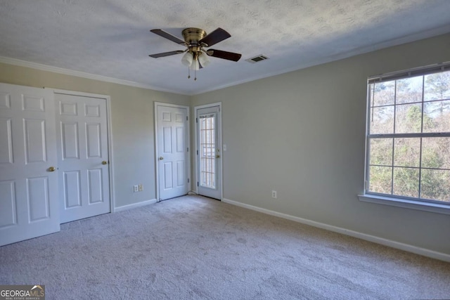 unfurnished bedroom featuring multiple windows, two closets, ceiling fan, and crown molding