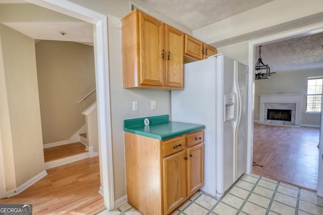 kitchen with a fireplace, white refrigerator with ice dispenser, and a chandelier