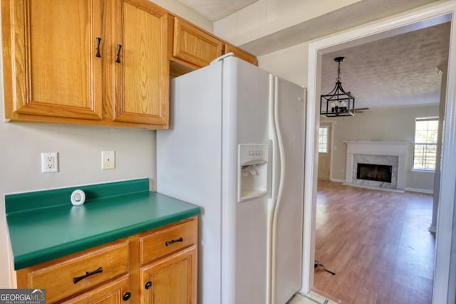 kitchen featuring hardwood / wood-style floors, a high end fireplace, a chandelier, and white refrigerator with ice dispenser