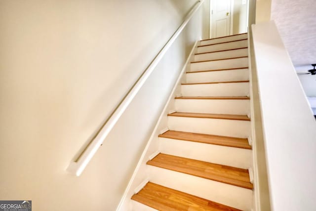 stairway featuring ceiling fan