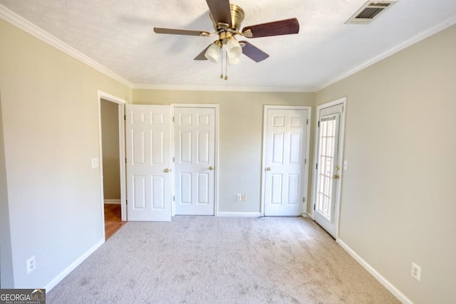 unfurnished bedroom featuring a textured ceiling, light colored carpet, ceiling fan, and crown molding