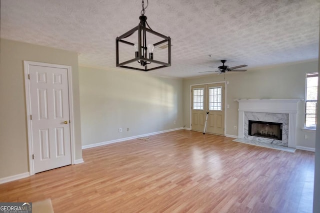 unfurnished living room featuring a textured ceiling, ceiling fan, light hardwood / wood-style floors, and a fireplace