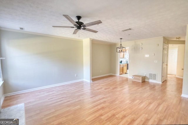 unfurnished living room featuring ceiling fan with notable chandelier, a textured ceiling, light wood-type flooring, and ornamental molding