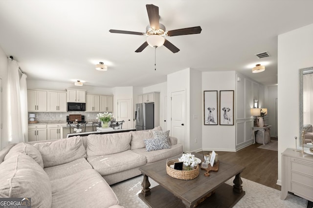 living room featuring wood-type flooring and ceiling fan